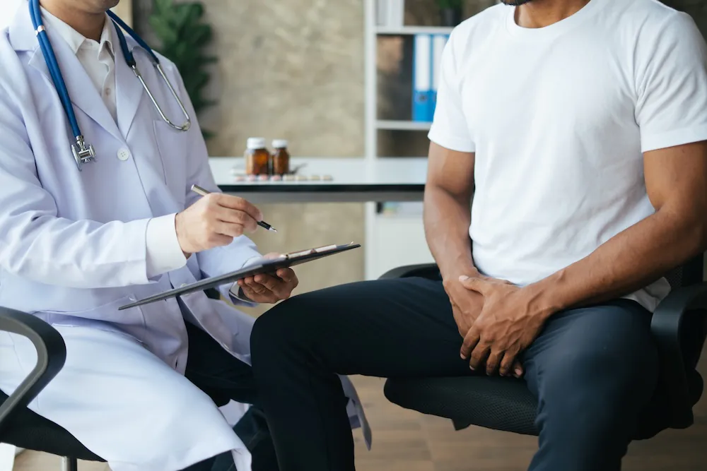 A doctor consulting a patient about premature ejaculation treatment in a clinical setting.
